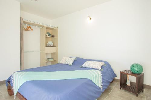 ein Schlafzimmer mit einem Bett mit einer blauen Decke in der Unterkunft Leu Jardin in Saint-Leu