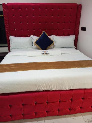 ein großes rotes Bett mit einem großen gepolsterten Kopfteil in der Unterkunft Hilton Garden Inn Ltd in Nsukka