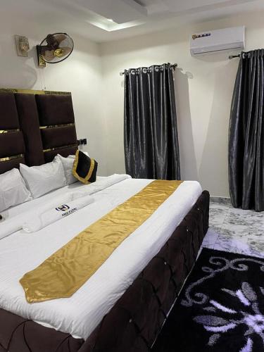 a bedroom with a large bed with a yellow blanket on it at Hilton Garden Inn Ltd in Nsukka