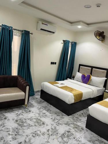 a bedroom with two beds and a couch and blue curtains at Hilton Garden Inn Ltd in Nsukka
