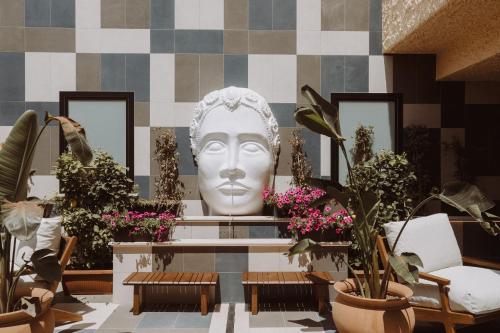 a large statue of a head in a room with plants at Mangia's Brucoli, Sicily, Autograph Collection in Brucoli