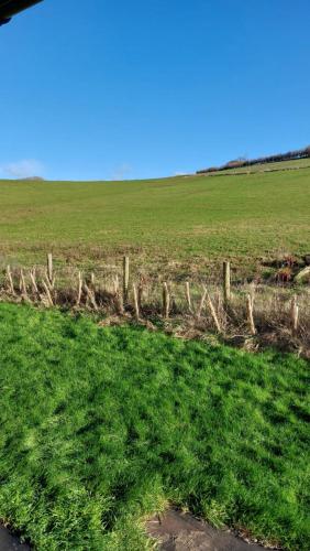 a fence in a field with a green field at Farm lodge in Shepton Mallet