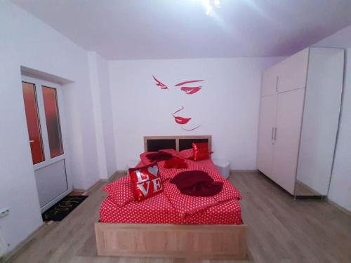 a bedroom with a red bed with a face painted on the wall at Cazare Centru Brasov in Braşov