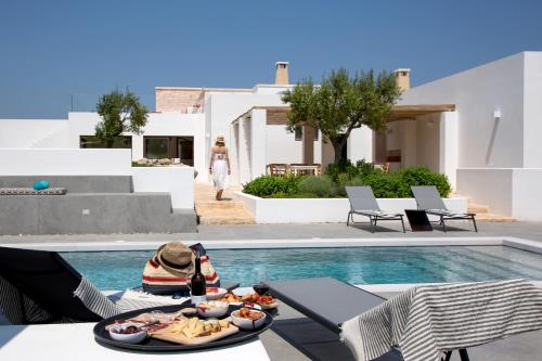 a table with a plate of food next to a swimming pool at Ddò Relais di Puglia in Ostuni