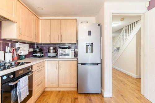 a white refrigerator in a kitchen with wooden cabinets at Spacious 3-bed Home - Nature Reserve Retreat in Ince-in-Makerfield