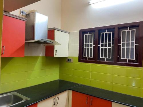 una cocina con armarios verdes y rojos y fregadero en Royal Experiences Peters Villa House, en Kuttālam