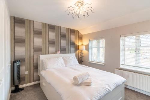 a bedroom with a white bed and a chandelier at Spacious 3-bed Home - Nature Reserve Retreat in Ince-in-Makerfield