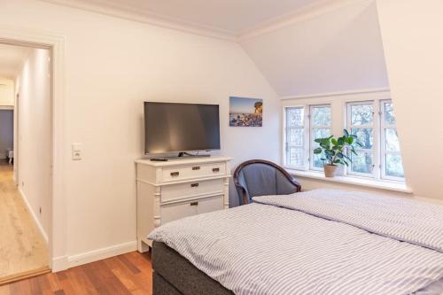 a bedroom with a bed and a flat screen tv at Gutshof Rothensande Herrenhaus in Waabs