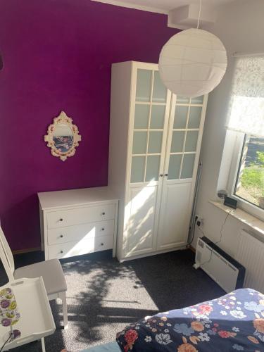 a bedroom with purple walls and a bed and a cabinet at Ferienwohnung Puttenusenhof in Klausdorf Brandenburg