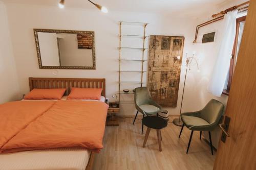 a bedroom with a bed and two chairs and a mirror at Wine & Art Lodge Jeruzalem in Ljutomer