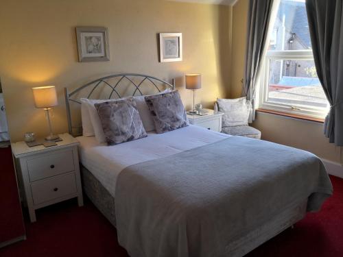 a bedroom with a large bed with two lamps and a window at Ashgrove House in Stratford-upon-Avon