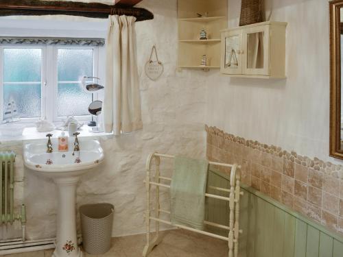 a bathroom with a sink and a mirror and a window at Wren Cottage in Cwm