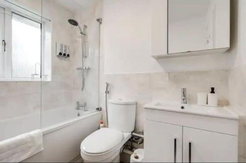 a white bathroom with a toilet and a sink at Newly renovated house near Trafford Centre in Manchester