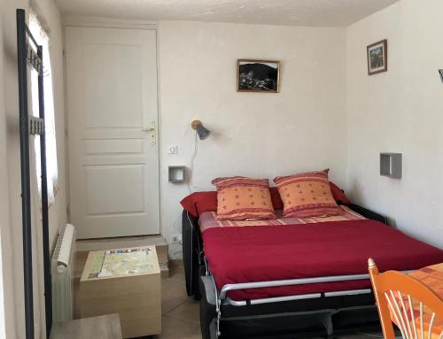 een slaapkamer met een bed met rode lakens en kussens bij Studio Lou Rigaou in Comps-sur-Artuby