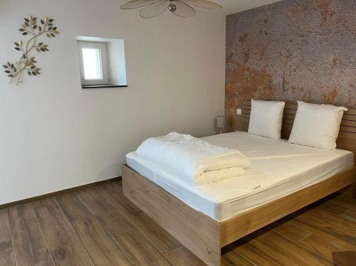 um quarto com uma cama grande e lençóis brancos em La Perle d'Alsace em Bernardswiller