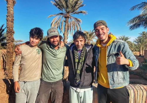 four men posing for a picture in front of a palm tree at Dar Toda - Zagora guest house in Zagora