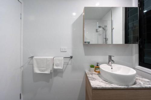 布里斯班Relaxation 2BR/1.5BA House w Parking near Beach的一间白色浴室，配有洗手池和镜子。