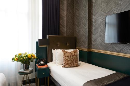 a bedroom with a bed with a television on the wall at The Portico Hotel in London