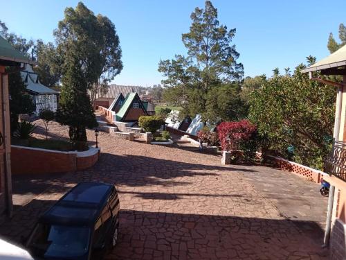 a brick driveway with trees and a house at Le Castel des Seigneurs in Antananarivo
