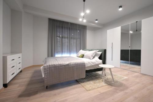 ein weißes Schlafzimmer mit einem Bett und einem Fenster in der Unterkunft City Center Luxury 2 Bedroom in Bukarest