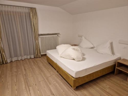 a bedroom with a bed with white sheets and a window at Apartment Aghel in Ortisei