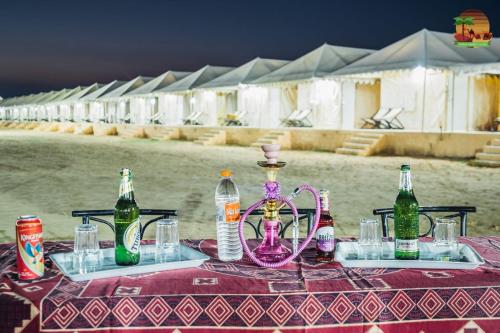 a table with a pink vase and bottles on it at Sam Desert Luxury Resort in Sām