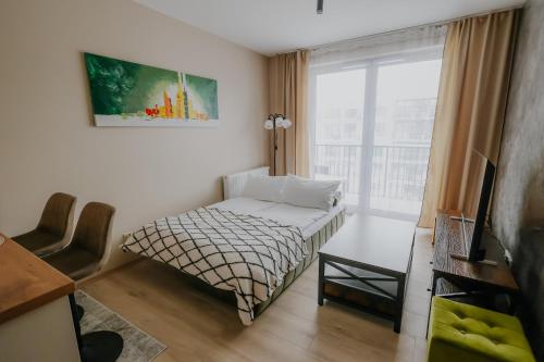 um pequeno quarto com uma cama e uma janela em Nowy Złocień Comfort Apartment em Cracóvia