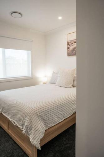 a white bedroom with a bed with a window at Sandy feet retreat in Peterborough