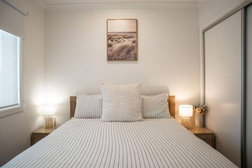 a bedroom with a large white bed with two lamps at Sandy feet retreat in Peterborough