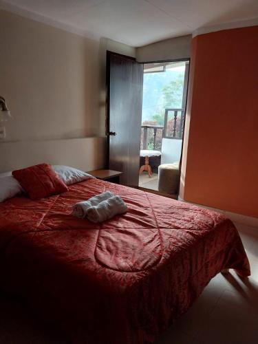 a bedroom with a bed with a red blanket and a window at Monte Gocta in Valera