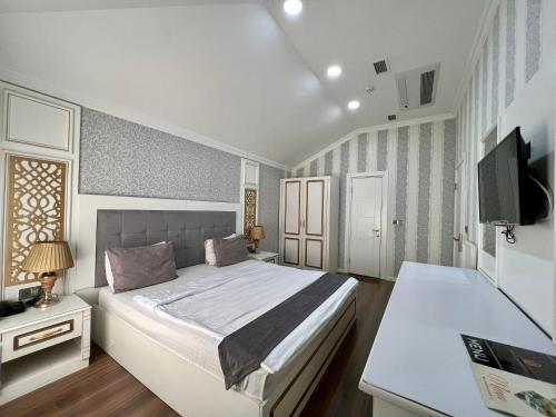 a bedroom with a large bed and a television at Mensen Hotel Baku in Baku