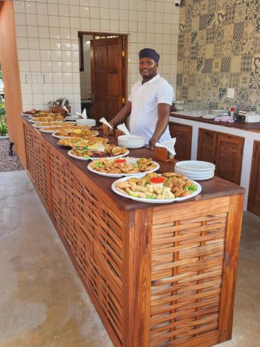 a man standing behind a buffet line with plates of food at Cabana Beach Lodge in Cabo Conguiane