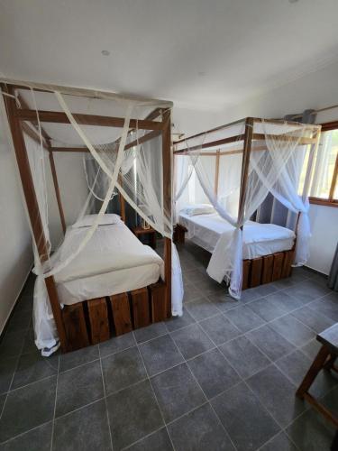 two beds with drapes in a room at Cabana Beach Lodge in Cabo Conguiane
