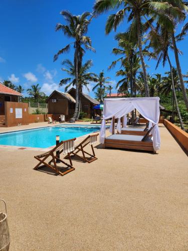 a swimming pool with a tent and benches next to a resort at Cabana Beach Lodge in Cabo Conguiane