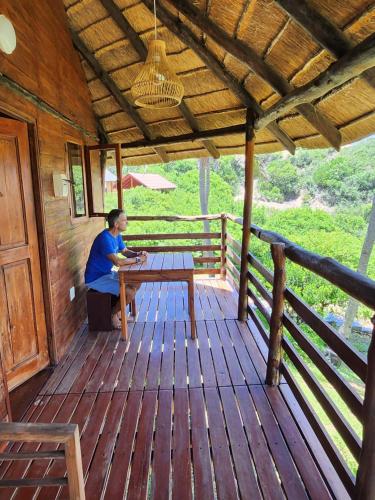 a woman sitting at a table on a wooden deck at Cabana Beach Lodge in Cabo Conguiane