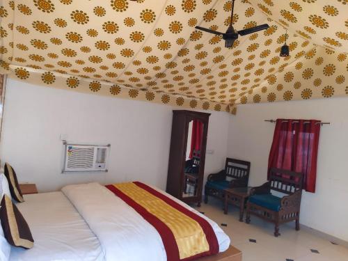 a bedroom with a bed and two chairs and a ceiling at Sam Desert Luxury Resort in Sām