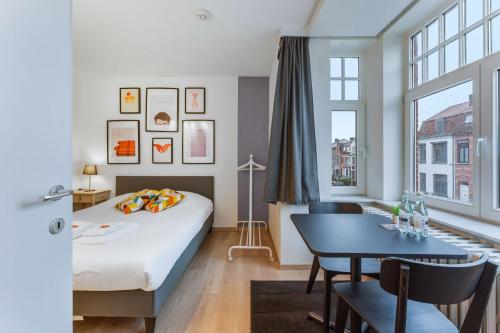 a bedroom with a bed and a table and a window at General Sixty-Seven by Romy&Travis in Bruges