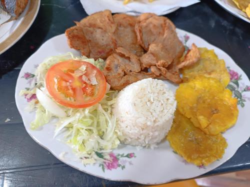 um prato de alimentos com arroz, carne e produtos hortícolas em Hostal mis dos ángeles em Santiago