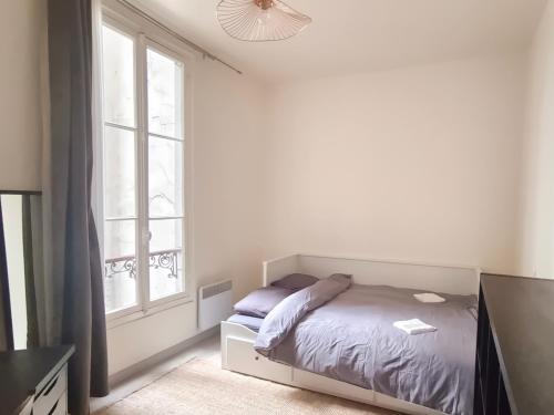 une chambre blanche avec un lit et une fenêtre dans l'établissement Bel appartement au Marais de Paris, à Paris