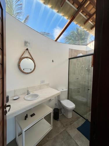 a bathroom with a toilet and a sink and a mirror at Pousada Villa Sagi in Baía Formosa