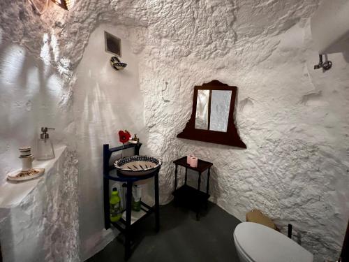a white bathroom with a toilet and a mirror at Cuevas La Veranda in Orce