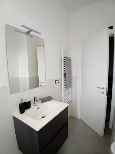 a white bathroom with a sink and a mirror at Loano: Centro e Mare a portata di mano in Loano
