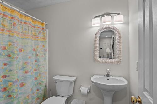 a bathroom with a toilet and a sink and a mirror at 7019 - Sara's Sea Breeze by Resort Realty in Rodanthe