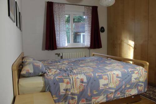 a bedroom with a bed with a comforter and a window at Ferienwohnung Erhard in Prien am Chiemsee