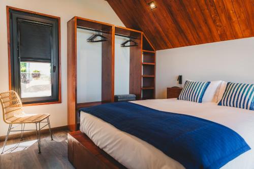 Un dormitorio con una cama y una silla y una ventana. en Cabanas do Pico 1A, en Canto da Areia