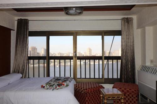 a bedroom with a bed and a large window at Jasmine Nile Sky Hotel in Cairo