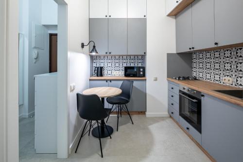 a kitchen with white cabinets and a table and chairs at Apartments on Krakowska street in Lviv