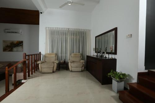 a living room with two chairs and a mirror at Eden Gardens Residence in Hokandara South