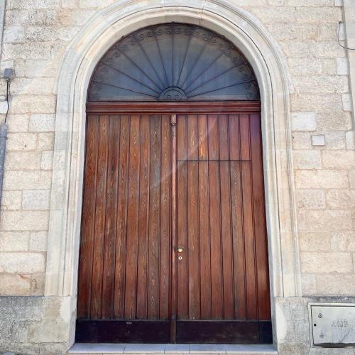 a large wooden door in a brick building at la casetta nel borgo wood in Borgagne