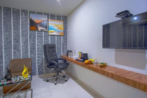 a room with a desk and a chair and a television at Hotel Limra in Surat